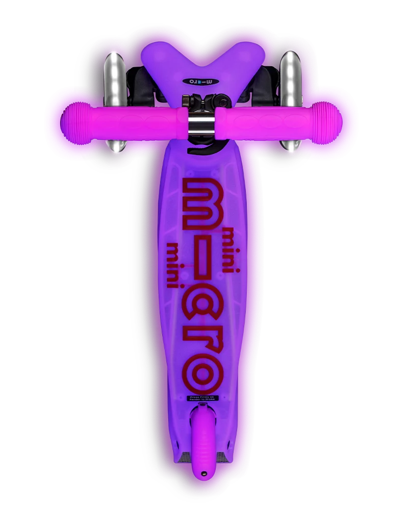 Scooter Mini Micro Deluxe Glow LED Frosty Pink rosado con tres ruedas luminosas, manubrio ajustable y detalles que brillan en la oscuridad.