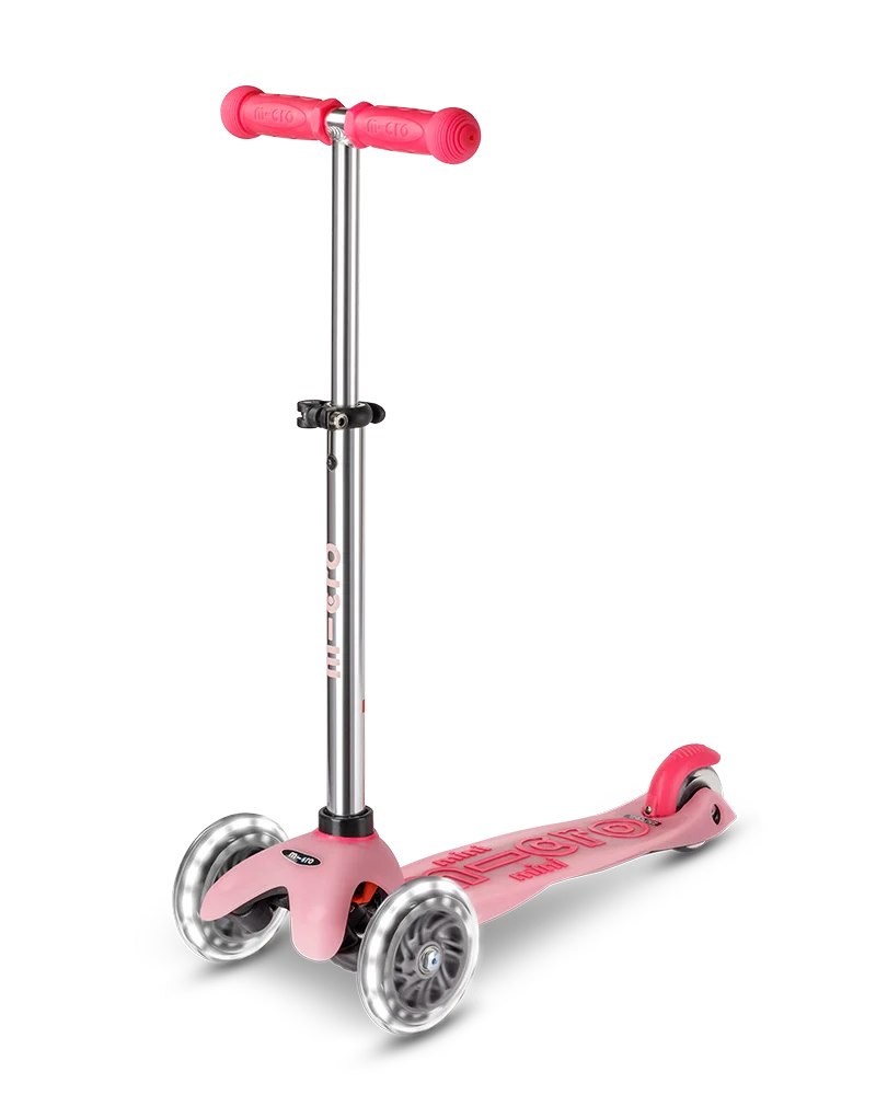 Scooter Mini Micro Deluxe Glow LED Frosty Pink rosado con tres ruedas luminosas, manubrio ajustable y detalles que brillan en la oscuridad.